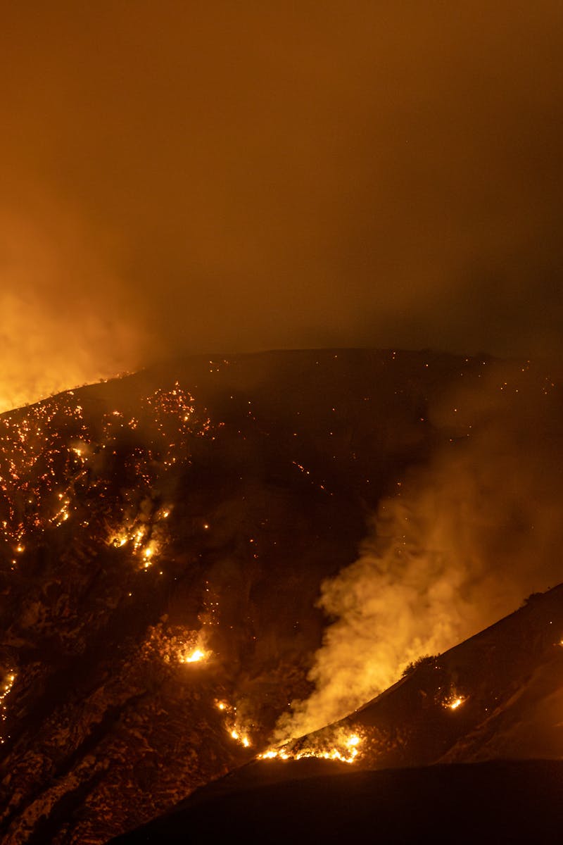 Intense wildfire blazing through mountains in California at night, creating a dramatic scene.